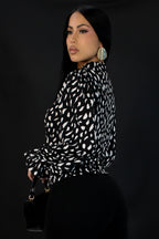 Woman wearing a black and white patterned blouse against a plain background