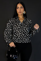 Woman wearing a black and white patterned blouse against a plain background