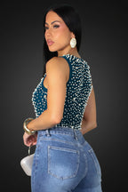 Woman wearing a blue polka dot top and jeans on a gray background