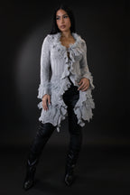 Woman wearing a long, light gray lace cardigan over a black outfit on a white background