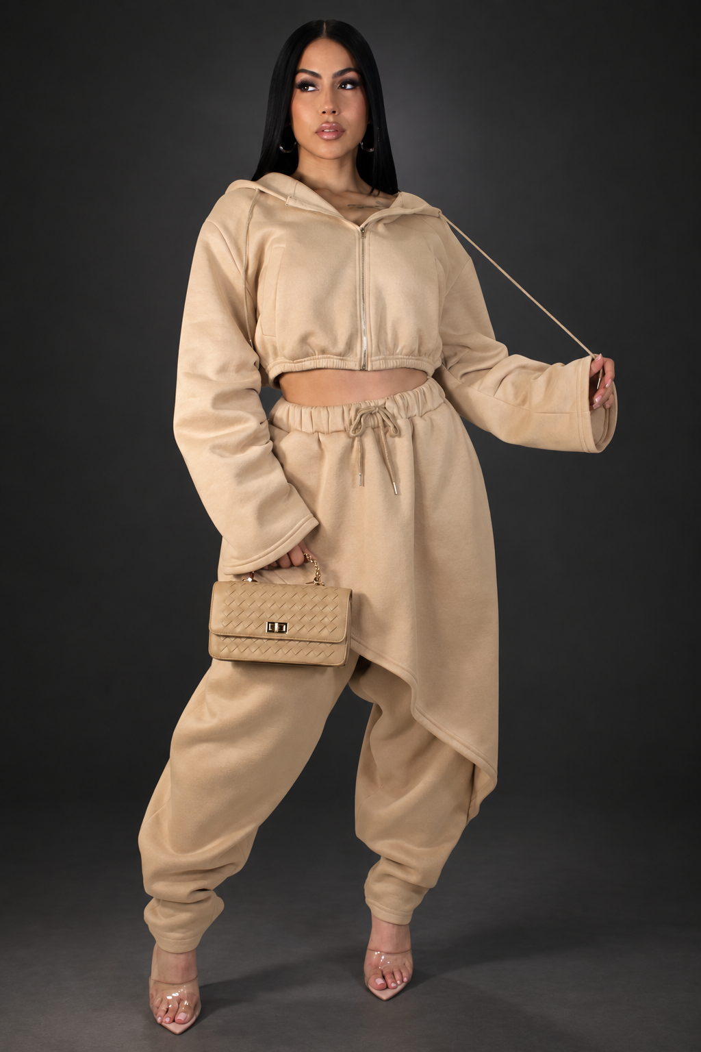 Model in tan pant set on a dark studio background