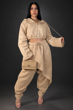 Model in tan pant set on a dark studio background